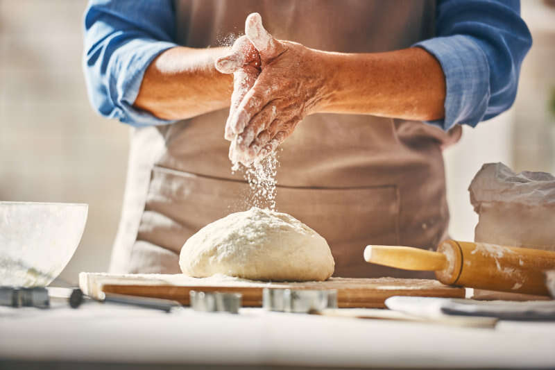 Panettiere lavora la pasta di pane con la farina Panettiere lavora la pasta di pane con la farina